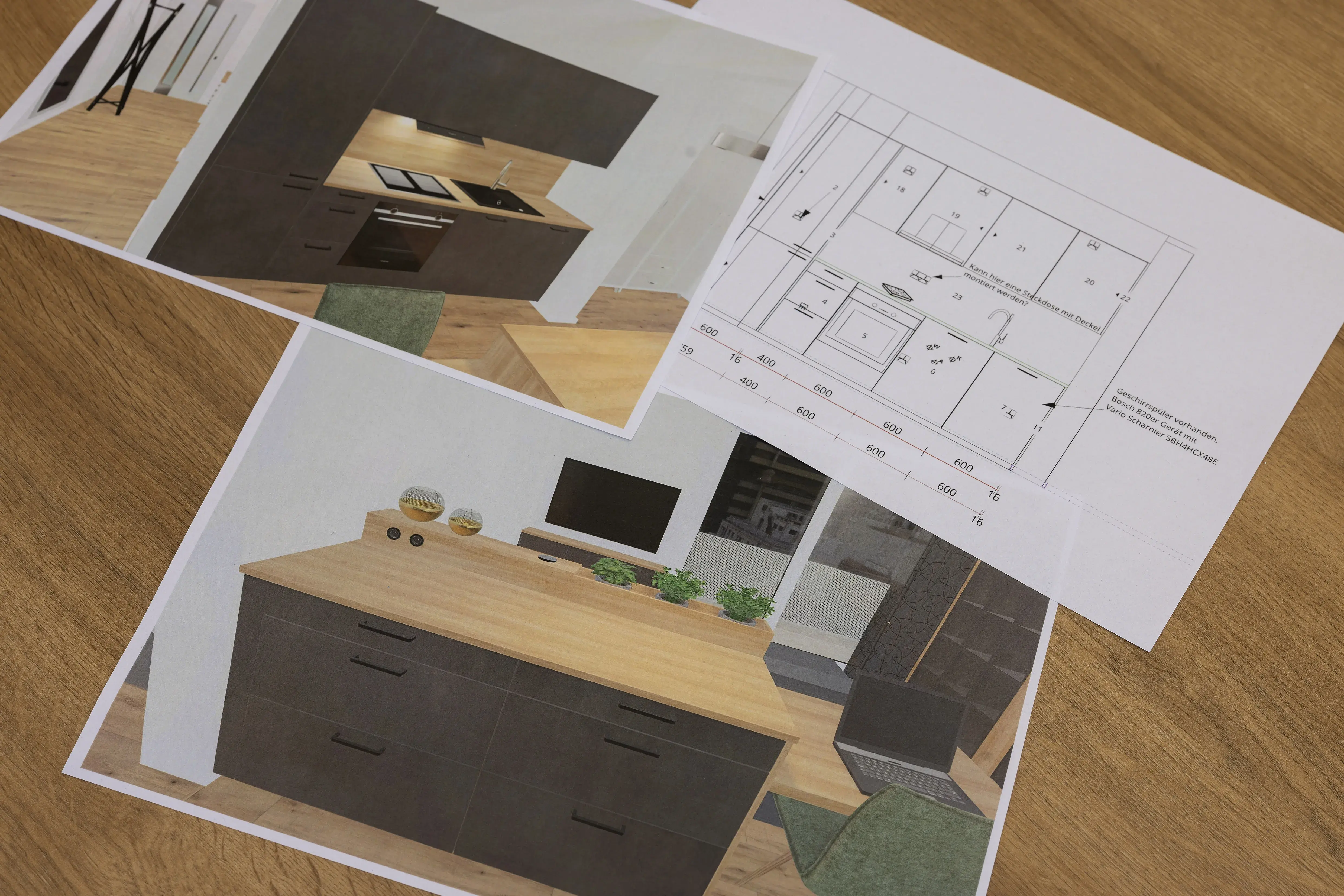Küchenentwürfe und Grundriss auf ausgedruckten Blättern auf einem Holztisch