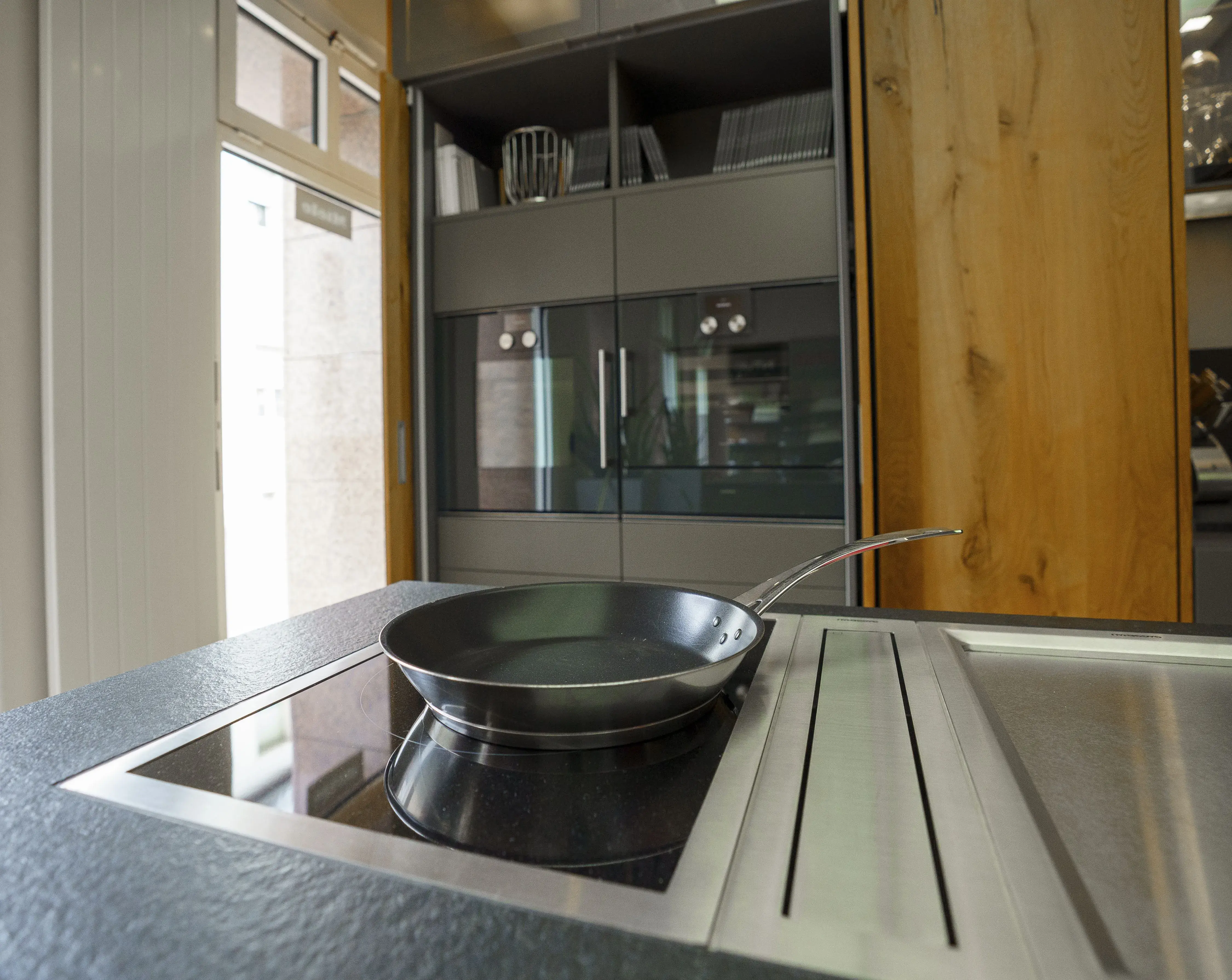 Foto von einem Kochfeld mit mittigem Abzug, dahinter Gaggenau Geräte in einem Hochschrank